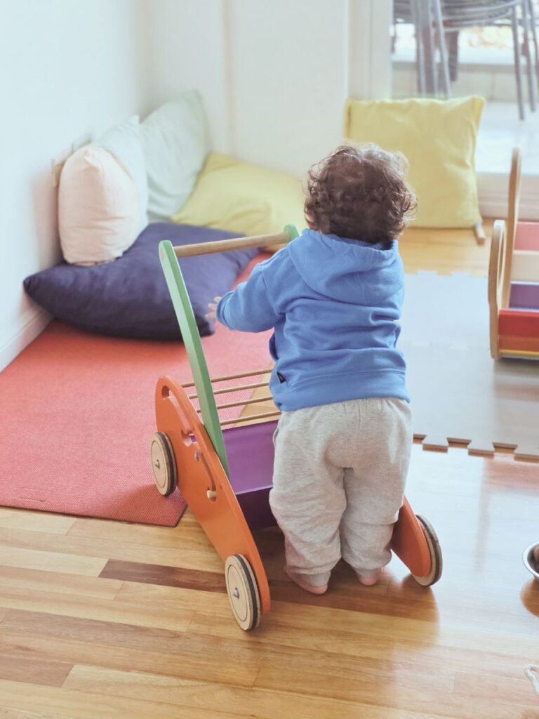 Bebé utilizando carro de empuje en un espacio de juego libre.