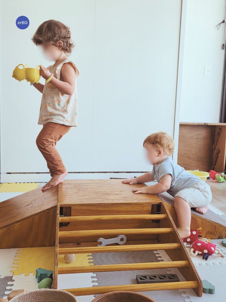 Bebé y niña pequeña subiendo y bajando en las rampas de gateo en espacio de juego libre