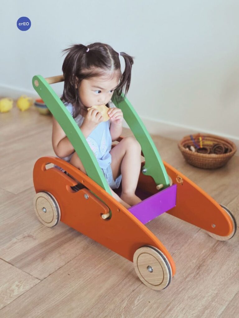 Bebé adentro de carro de empuje en un espacio de juego libre.