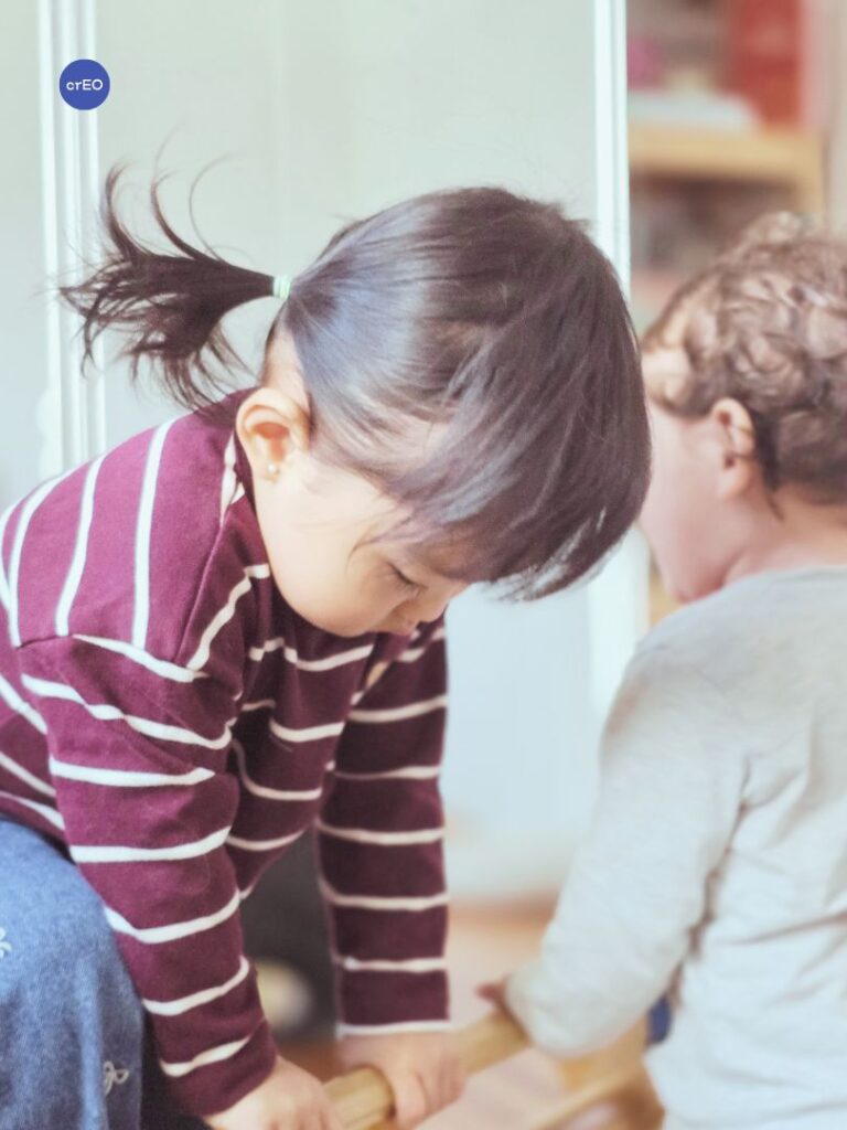 Bebés trepando el triángulo Pikler, aprendiendo a compartir el espacio con pares en un grupo de juego libre.