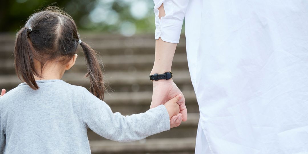 Niña tomando de la mano a su mama