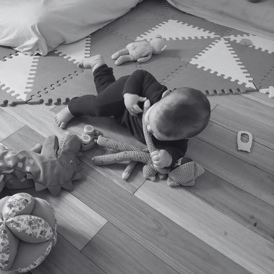 Bebé en el piso interactuando con objetos simples mientras organiza su movimiento de forma autónoma.