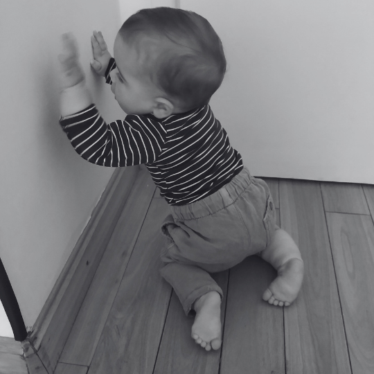 Bebé explorando la verticalidad y el apoyo del cuerpo en contacto con una pared.