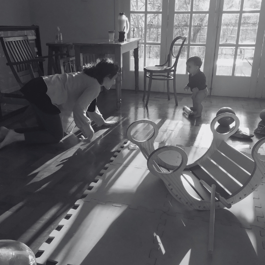 Adulto a la altura del piso acompañando el movimiento espontáneo de un bebé sin intervenir.