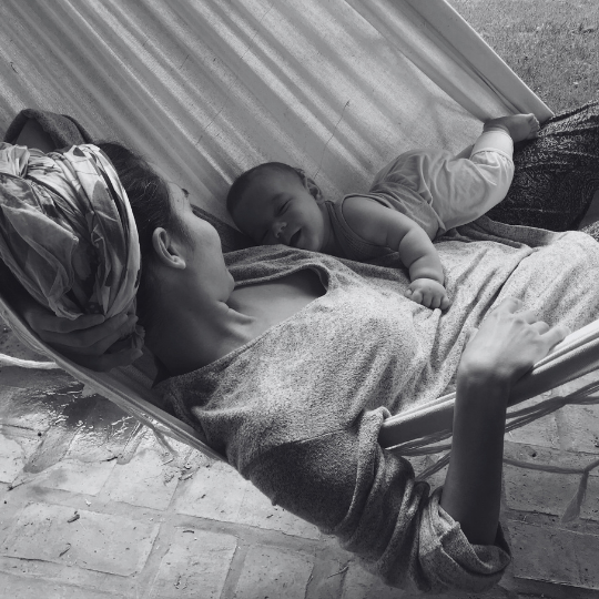 Adulto recostado ofreciendo sostén corporal a un bebé en un momento de descanso.