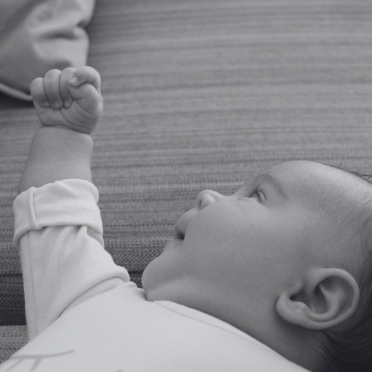 Bebé observando su propia mano mientras explora el movimiento y la coordinación.