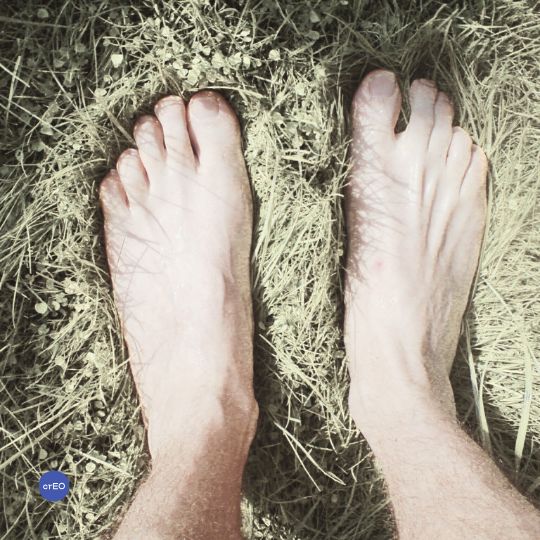 Pies descalzos de un adulto en contacto con el suelo, mostrando apoyo y conexión corporal.