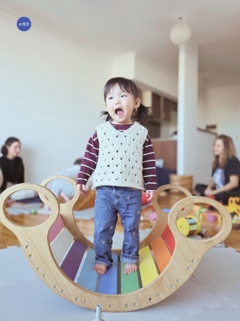 Hamaca balancín de madera en uso por una niña pequeña durante una actividad de juego libre.