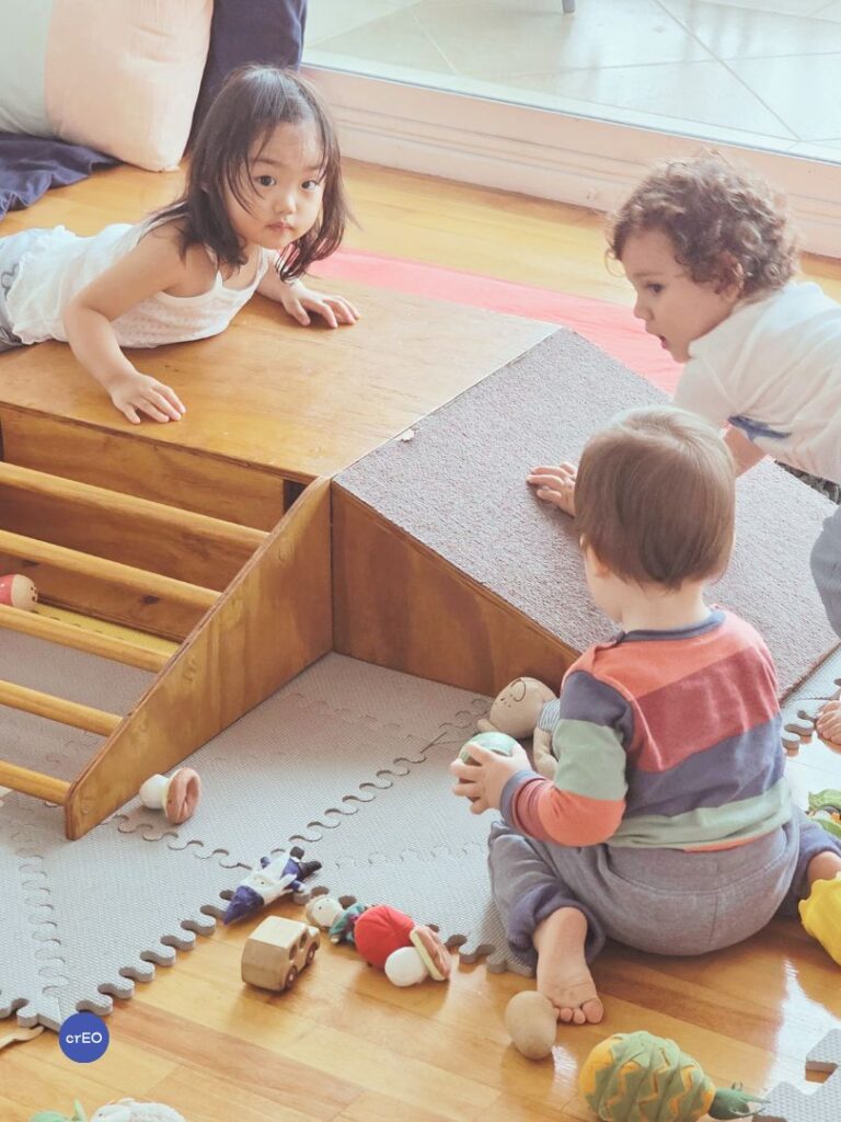 Bebés explorando una rampa de gateo de madera, probando el movimiento con su propio cuerpo.