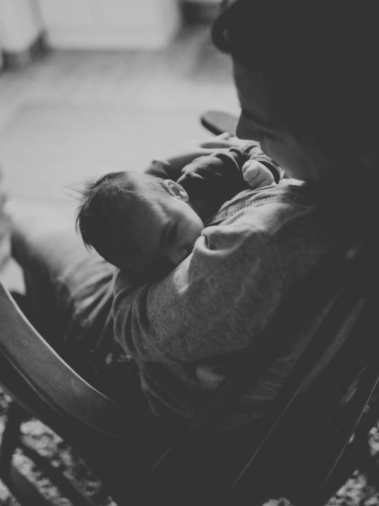 Sueño infantil y apego: bebé tomando la teta en silla mecedora